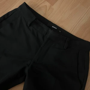 Svarta kostymbyxor från Bik Bok - Snygga svarta kostymbyxor från Bik Bok med en klassisk design. Byxorna har en rak passform och är perfekta för en stilren look men är även bekväma att ha på sig. Använda en gång. Säljer då de inte passar mig💕💕