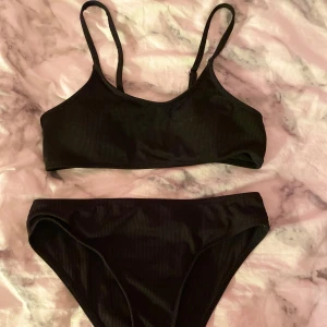 Svart bikini  - Svart ribbad bikini med justerbara axelband. Stl 150 passar dig som bär på S. Från shein använda ett par gånger men som nya. Finns även kuddar på överdelen. Kommer inte till användning 