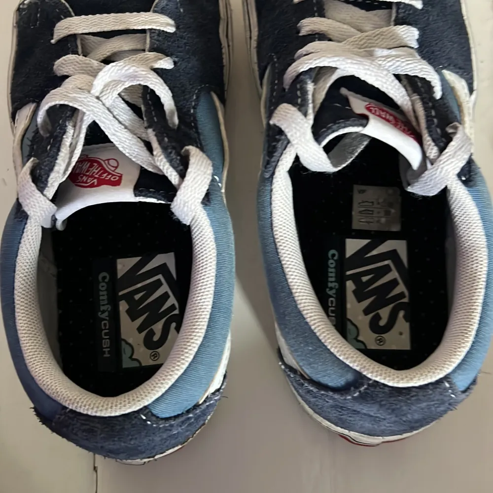 Säljer ett par klassiska Vans sneakers i blått och vitt. Skorna har en snygg design med vita snören och den ikoniska Vans-loggan på hälen. Perfekta för en avslappnad stil.. Kengät.