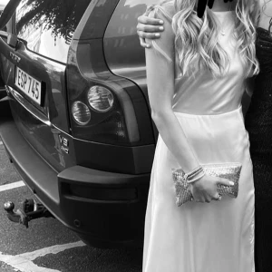 Ljusrosa balklänning - Elegant ljusrosa balklänning med v-ringad design och spetsdetaljer. Klänningen har en slits på sidan och är ärmlös, vilket ger en stilren och sofistikerad look. Den har några små fläckar längst ner men det är inget man tänker på(se bild 4)