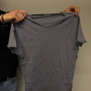 Grå t-shirt från Filippa K - Säljer en stilren grå t-shirt från Filippa K. Den har en klassisk rund hals och korta ärmar, perfekt för en avslappnad look. Gjord i mjukt material som känns skönt mot huden. Passar till det mesta i garderoben!
