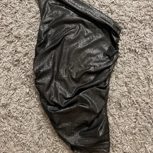 Svart glittrig topp - Snygg svart glittrig topp med en tight passform. Perfekt för en kväll ute eller en festlig tillställning. 