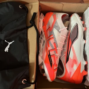 Puma Ultra 5 - Helt nya fotbollsskor från Puma i vitt, rött och svart. Levereras med en praktisk svart förvaringspåse med Puma-logga. Storlek 43.    Ny pris: 1800