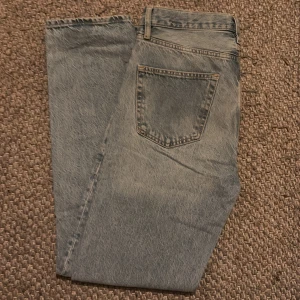Ljusblå jeansbyxor - Säljer ett par klassiska ljusblå jeansbyxor med en rak passform. De har en traditionell femficksdesign och är tillverkade i slitstarkt denim. Perfekta för en avslappnad stil.