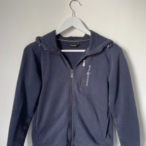 Hoodie, Sail Racing  - Säljer en mörkblå hoodie från Sail Racing med dragkedja och huva. Den är i storleken XS. Hör av er vid intresse, Pris kan diskuteras!