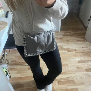 Grå Tiamo väska!  - Grå snygg Tiamo väska. Köpt för cirka 2 år sedan men inte använt den sedan 1 år tillbaka. Den har inga täcken på rost på kedjan och inte heller några andra större defekter. Nypris 500kr. Hör av er vid frågor!🩷Kan tänka mig sänka vid snabb affär och seriös köpare. (köparen står för frakten) 