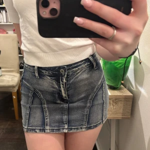 Jeans minikjol i blå denim - Snygg kort jeanskjol i blå denim med slitna detaljer och knappstängning fram. Kjolen är en stor favorit! 