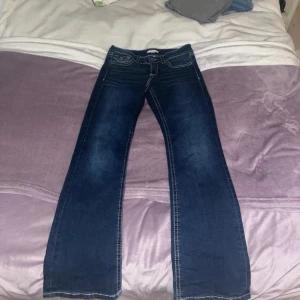 Lågmidjade Blå jeans från Gina Tricot - Snygga blå jeans från Gina Tricot med bootcut-stil. De har en klassisk femficksdesign och knappar bak på fickorna. Perfekta för en avslappnad look. Storlek 164 men passar som XS. Priset kan diskuteras.