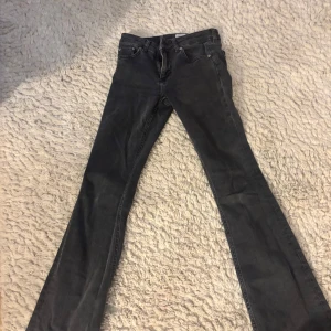 Svarta bootcut jeans - Snygga svarta bootcut jeans med klassisk femficksdesign. De har en dragkedja och knapp framtill. Perfekta för en stilren look. Lågmidjade