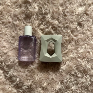 Parfym från Ariana Grande - Elegant parfym med en unik geometrisk design. Flaskan är lila och rektangulär med en vit kork. Den vita ytterförpackningen har en modern, facetterad form som ger ett stilrent intryck. Perfekt för den som söker en doft med både stil och karaktär. Har själv bara tagit några sprut av parfymen då jag redan har en men skulle själv säga att parfymen doftar väldigt gott🍁☀️🙏🏼😍💓🍰