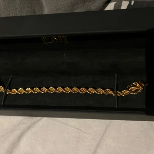 Guldarmband från Kejsar - Elegant guldarmband från Kejsar med en vriden design. Perfekt för att lägga till en touch av lyx till din stil. Kommer i en snygg svart förpackning. Det är 18,5cm långt.