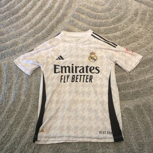 Vit Real Madrid fotbollströja - Säljer en vit Real Madrid fotbollströja. PRIS KAN DISKUTERAS jag är 160 och den passar mig bra