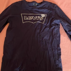 Mörkblå långärmad tröja från Levi's - Säljer en svart långärmad tröja från Levi's med deras ikoniska logga tryckt på bröstet. Perfekt för en avslappnad stil och enkel att matcha med jeans eller chinos. Passar både till vardags och mer avslappnade tillfällen.