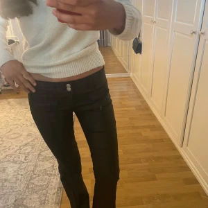 Svarta bootcut byxor från Nelly - Säljer ett par svarta bootcut skinnbyxor byxor från Nelly i storlek 36. Byxorna har låg midja, två knappar framtill och 2 snygga  framfickor dem är klippta för den var för långa men dem passar mig i längden bra som är 164 dem är helt slutsålda på Nelly klöppta för 700