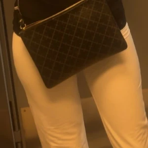 Svart rutig axelväska med dragkedja - Snygg svart axelväska med rutigt mönster och praktisk dragkedja upptill. Perfekt storlek för att få plats med mobilen, plånboken och lite till. Väskan har en stilren look som passar till många outfits.