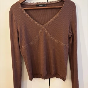 Brun ribbad topp med spets  - en brun långärmad topp  i ribbad bomull med v-ringning 