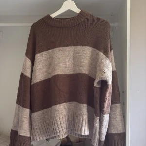 Randig stickad tröja i brunt och beige - Säljer en oversized stickad tröja från NAKD. Aldrig använd har bara legat i garderoben🤎🤍 