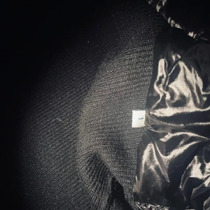 Svart pufferjacka från Moncler med huva - Kan går ner i pris vid  en snabb och smidig affär   Snygg svart pufferjacka från Moncler med glansig quiltad front och huva. Ärmarna är stickade och har Moncler-logga på vänster arm. Jackan har dragkedja och snörning i huvan, perfekt för kalla dagar. Riktigt stilren och sportig vibe.