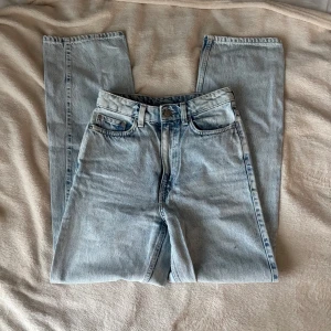 Weekday Rowe ljusblå raka jeans - Säljer ett par Weekday Rowe jeans i ljusblå tvätt med  hög midja och raka ben. Klassisk femficksmodell i 100% bomull. Fint skick. Innebenslängd 75 cm