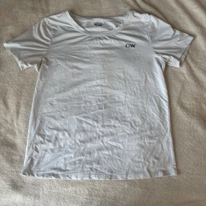 Vit tränings t-shirt från ICANIWILL -  vit tränings t-shirt från ICANIWILL med svart logga på bröstet. T-shirten har rund halsringning och är kortärmad. Sparsamt använd. 