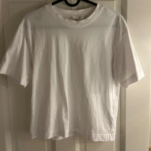 Vit basic t-shirt i bomull - Enkel och stilren vit t-shirt med rund hals och korta ärmar. Perfekt för en clean look och lätt att matcha med allt. Tillverkad i mjuk bomull som känns skön mot huden.