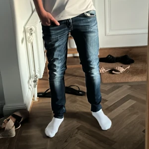 Dondup George Skinny Fit Jeans Blå - Säljer ett par Dondup George skinny fit jeans i klassisk blå tvätt. Jeansen har smal passform, snygga slitningar och detaljerad tvätt för en modern look. Tillverkade i bomull med stretch för extra komfort. Perfekta för dig som gillar en tight och stilren stil. Den ändå defekten är den bruna tagen i jeansen. Är för små för mig och är 180 och väger 67kg