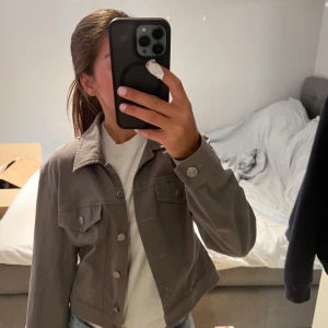Grå jeansjacka från Intense, strl 38 - Snygg grå jeansjacka från Intense i storlek 38. Klassisk modell med krage, bröstfickor med knappar och raka sömmar. Jackan är tillverkad i bomull med lite stretch för extra komfort. Perfekt att slänga över en hoodie eller t-shirt.