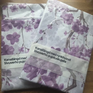 2 st Kanallängder / gardiner, 140x240 cm - Bilderna visar två paket med gardiner från Hemtex, med lila blommönster och kanal för rynkhuvud. Nyskick, oanvända. Obruten förpackning. Inköpt för 199kr/st. 