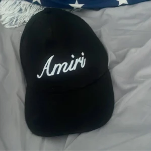 Svart keps från Amiri - Svart keps från Amiri med vit broderad logga framtill. Klassisk böjd skärm och justerbar passform. Perfekt accessoar för en cool och avslappnad stil.