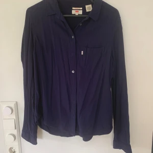 Mörkblå skjorta från Levi's, classic fit - Säljer en mörkblå skjorta från Levi's i classic fit. Skjortan har lång ärm, bröstficka och knappar.  Materialet känns mjukt och lätt, och färgen är djupblå. Den är rynkig då den inte är strykt. I jättefint skick! Hör av er om ni har frågor eller vill ha mer bilder🤗🤗