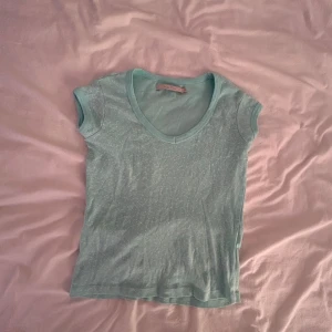 Ljusblå t-shirt från Part Two - Snygg ljusblå t-shirt från Part Two med diskret vitt mönster och v-ringning. Modellen är kortärmad och har en klassisk passform i mjuk bomull. Perfekt till jeans eller kjol för en chill look.