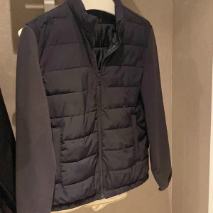 Cardigan, Zara  - Snygg svart/marinblå pufferjacka med quiltad front och släta ärmar. Jackan har dragkedja hela vägen, ståkrage och två fickor framtill. Perfekt för kyliga dagar och enkel att matcha med allt. Stilren och modern look.