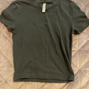 Svart basic t-shirt från H&M Divided , 140/146 - En enkel svart t-shirt från H&M Divided Basic. Modellen är klassisk med rund hals och korta ärmar, perfekt för en clean och chill look. Materialet är mjuk bomull som känns skönt mot huden. Passformen är normal och funkar till allt.