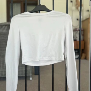 Vit croppad långärmad topp Shein - En basic vit croppad långärmad topp från Shein. Enkel och stilren design med rund halsringning och tight passform. Perfekt att matcha med höga jeans eller kjol för en clean look.
