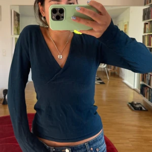 Mörkblå omlottstickad tröja - Supersnygg mörkblå stickad tröja med omlott och v-ringad hals. Tröjan har långärmade ärmar och sitter slim på kroppen
