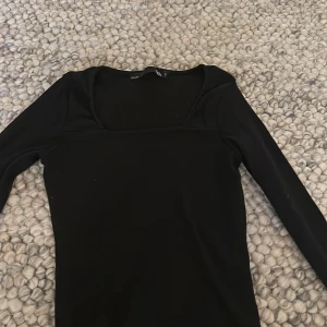 Svart långärmad topp från 157 - Svart långärmad topp från lager 157 med fyrkantig ringning och ribbad struktur. Sitter tajt och är perfekt att styla med jeans eller kjol. Enkel och stilren design som funkar till många olika looks.