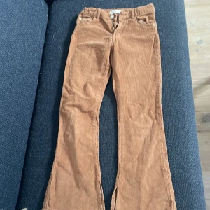 Bruna manchesterbyxor från Zara - Snygga bruna manchesterbyxor från Zara i storlek 152. Byxorna har klassisk femficksdesign, bootcut-ben och dragkedja med knapp framtill. Perfekta för dig som gillar retrovibbar och mjukt material.