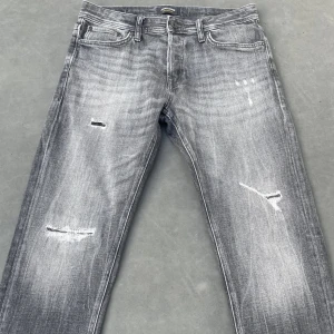 Mörkgrå Jack & Jones Jeans - Säljer dessa Jack & Jones jeans i extremt bra skick utan skador eller defekter. Färgen är mörkare i verkligheten men med utomhus ljus blir det lite mer gråare . Hör av er vid frågor eller funderingar!! Strl 30/30