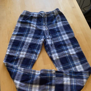 Pyjamas - Säljer ett par sköna mjukisbyxor i blått och vitt rutigt mönster. Byxorna har dragsko i midjan för perfekt passform och är gjorda i mjukt bomullstyg. Perfekta för chill dagar hemma eller när du vill vara extra bekväm. Säljer dem för att dem är för små