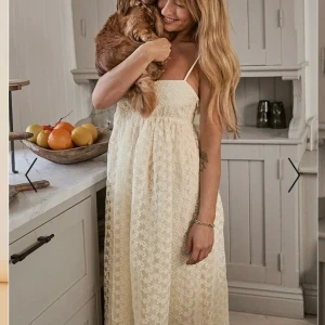 Strap detail midi dress - Superfin gräddfärgad långklänning från NA-KD  med tunna axelband och blommigt spetstyg. I storlek 34. Från NA-KD x Sanna Jörviks kollektionen. Köpte den på vinted men den är helt ny och alla lappar sitter kvar. Säljer då den är lite för stor i bysten. Jag är 156 lång🩵