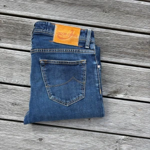 Jacob Cohen blå jeans style 688 - Snygga blå jeans från Jacob Cohen, modell style 688. Klassisk femficksdesign med kontrastsömmar och exklusiv patch i brunt på bakfickan. Jeansen har rak/slim passform och är tillverkade i mjukt jeansmaterial med detaljerad insida. Perfekt för dig som gillar stilrena och tidlösa jeans. W31, kom gärna med frågor🙌