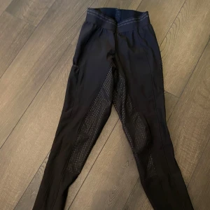 Svarta ridbyxor från Pikeur - Snygga svarta ridbyxor från Pikeur med prickigt mönster och dekorativa detaljer. Byxorna har en tight passform och är perfekta för ridning. Materialet är syntetiskt och ger bra rörelsefrihet. Tyvärr har några glitter pärlor trillat av men de syns inte mycket! 
