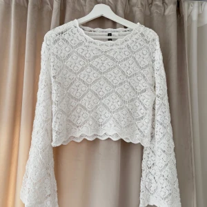 Vit spetsmönstrad tröja från H&M Divided - Säljer en vit spetsmönstrad tröja från H&M . Tröjan har långa ärmar och ett vackert spetsmönster framtill. Perfekt för en stilren look. 💫