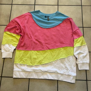 Flerfärgad tröja från Rainbow storlek 44/46 - Säljer en färgglad tröja från Rainbow i storlek M. Tröjan har blockfärger i blått, rosa, gult och vitt. Den är långärmad och tillverkad av bomull, vilket gör den bekväm och mjuk. Perfekt för en avslappnad stil!