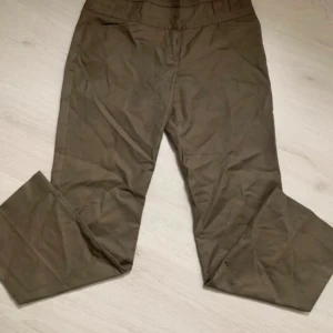 Bruna byxor - Säljer ett par bruna byxor med normal passform. Byxorna har en klassisk design med raka ben och är perfekta för en avslappnad stil. De har en enkel midja och är tillverkade i ett bekvämt material.