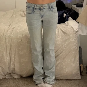 Ljusblå bootcut jeans - Säljer ett par ljusblå bootcut jeans med låg midja. De har en klassisk femficksdesign och är perfekta för en avslappnad stil. Jeansen har en snygg tvätt som ger dem en vintagekänsla.