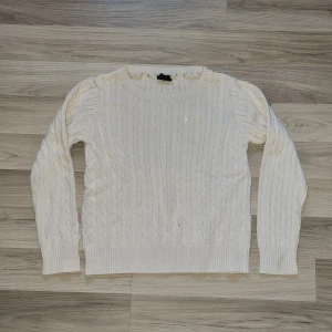 Vit stickad tröja från Cubus - Säljer en stilren vit stickad tröja från Cubus. Tröjan har ett klassiskt flätmönster och långa ärmar. Passar bra till både jeans och kjol. Är märkt som storlek L men upplever den mer som en storlek S.