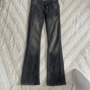 Grå bootcut jeans från Dr. Denim - Snygga grå bootcut jeans från Dr. Denim med en cool tvättad look. De har hög midja och två knappar i gylfen. Perfekta för en trendig stil! NYSKICK ENDAST PRÖVADE
