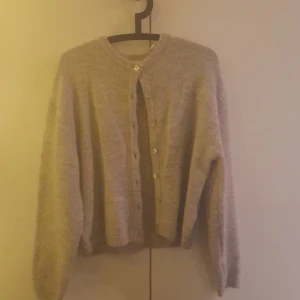 Grå kofta från Gina Tricot stl S - Mysig grå kofta från Gina Tricot i ullblandning. Den har en klassisk design med knappar framtill och ribbade kanter. Perfekt för kyliga dagar. Aldrig använd, storlek S