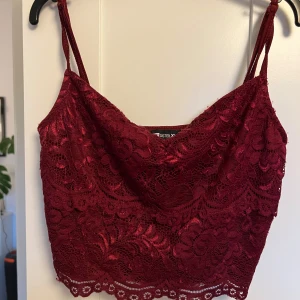Vinröd spetslinne från FB Sister - Säljer ett snyggt vinrött spetslinne från New Yorker. Linnet har tunna axelband och ett vackert blommigt spetsmönster. Perfekt för en kväll ute eller en speciell tillställning. 💃